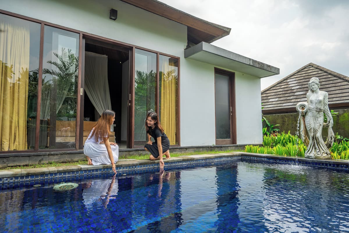 A swimming pool with a statue, a building with large windows, and a person by the pool.