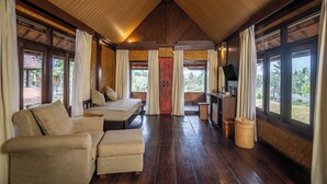 A room with a wooden ceiling, large windows, a bed, a sofa, a TV, and a small table. - Alpin Resort and Villa Ubud (Ubud)