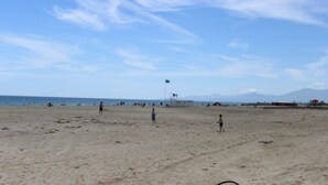 A beach with a flag, people, and a clear sky. - Large villa with garden / 6 persons / 300 m from the sea (Canet-en-Roussillon)
