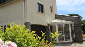 A modern building with a curved facade, a glass enclosure, and a stone accent wall. - Large villa with garden / 6 persons / 300 m from the sea (Canet-en-Roussillon)