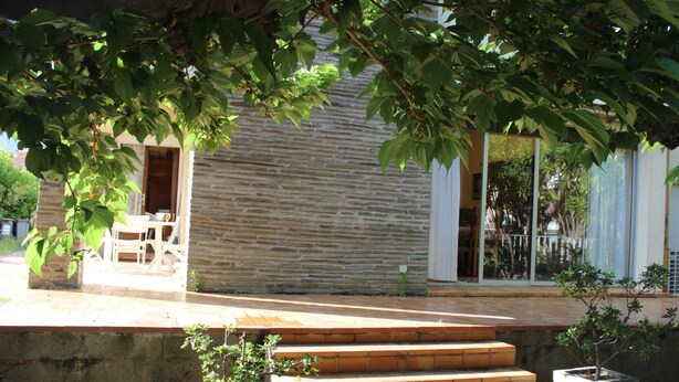 A stone building with a wooden door, a set of outdoor stairs, and a potted plant. - Large villa with garden / 6 persons / 300 m from the sea (Canet-en-Roussillon)