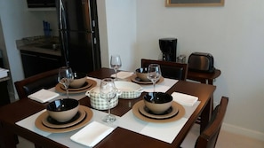 A dining table set with bowls, plates, and glasses, with a coffee maker and toaster on the side. - Legaspi Park Apartments (Makati)