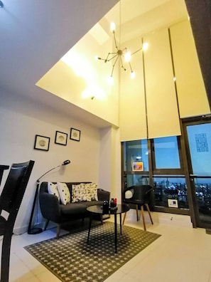 Ein modernes Wohnzimmer mit Sofa, Sesseln, einem Couchtisch und einem großen Fenster mit Blick auf die Stadt.
