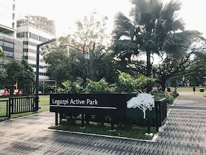Schild für den Legazpi Active Park mit Baumgrafik, umgeben von Grünflächen und einem gepflasterten Weg.