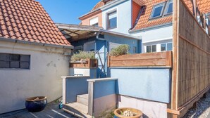 A courtyard with a wooden fence, a blue building, and a red-tiled roof. - Fitters' accommodation Kuddel (Laboe)