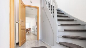 A staircase with carpeted steps, a wooden door, and a view into a dining area. - Fitters' accommodation Kuddel (Laboe)