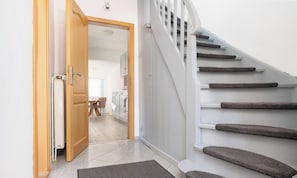 Un escalier avec des marches recouvertes de moquette, une porte en bois et une vue sur une salle à manger.