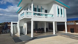Uma casa de dois andares com varanda, piscina e área de varanda coberta.