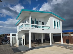 Una casa de dos pisos con balcón, piscina y terraza cubierta.