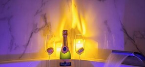 A bottle of Delagne wine, two glasses, and a candle in a room with marble walls. - Love in The Jungle: Sauna, Jacuzzi & Private Parking (Le Mans)