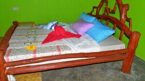 Ein Bett mit einer blumigen Tagesdecke, mehreren Kissen und einer roten Decke.