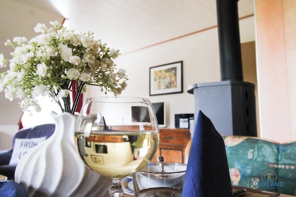 A room with a fireplace, a vase with flowers, a wine glass, and a sofa. - Apartment Medemblick with canoe dock - Ihlienworth (Ihlienworth)