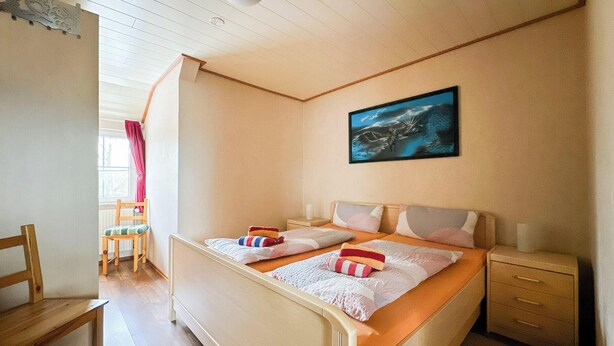 Un dormitorio con dos camas, una ventana con cortinas, una mesita de noche y un cuadro en la pared.