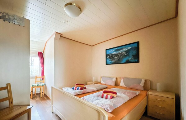 A bedroom with two beds, a window with curtains, a bedside table, and a painting on the wall. - Apartment Medemblick with canoe dock - Ihlienworth (Ihlienworth)