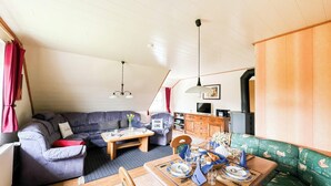 Un espacio de sala acogedor con un sofá, una mesa de comedor para dos, un televisor y una chimenea.