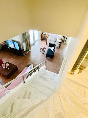 A spacious living area with a flat-screen TV, a dark sofa, and a dining area with chairs and a table. - Villa Violetta Country House with Mountain View, Private Balcony and Garden (Kavala)