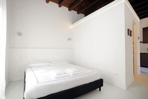 Ein modernes Schlafzimmer mit einem weißen Bett, einer schwarzen Kopfteil und weißen Wänden.