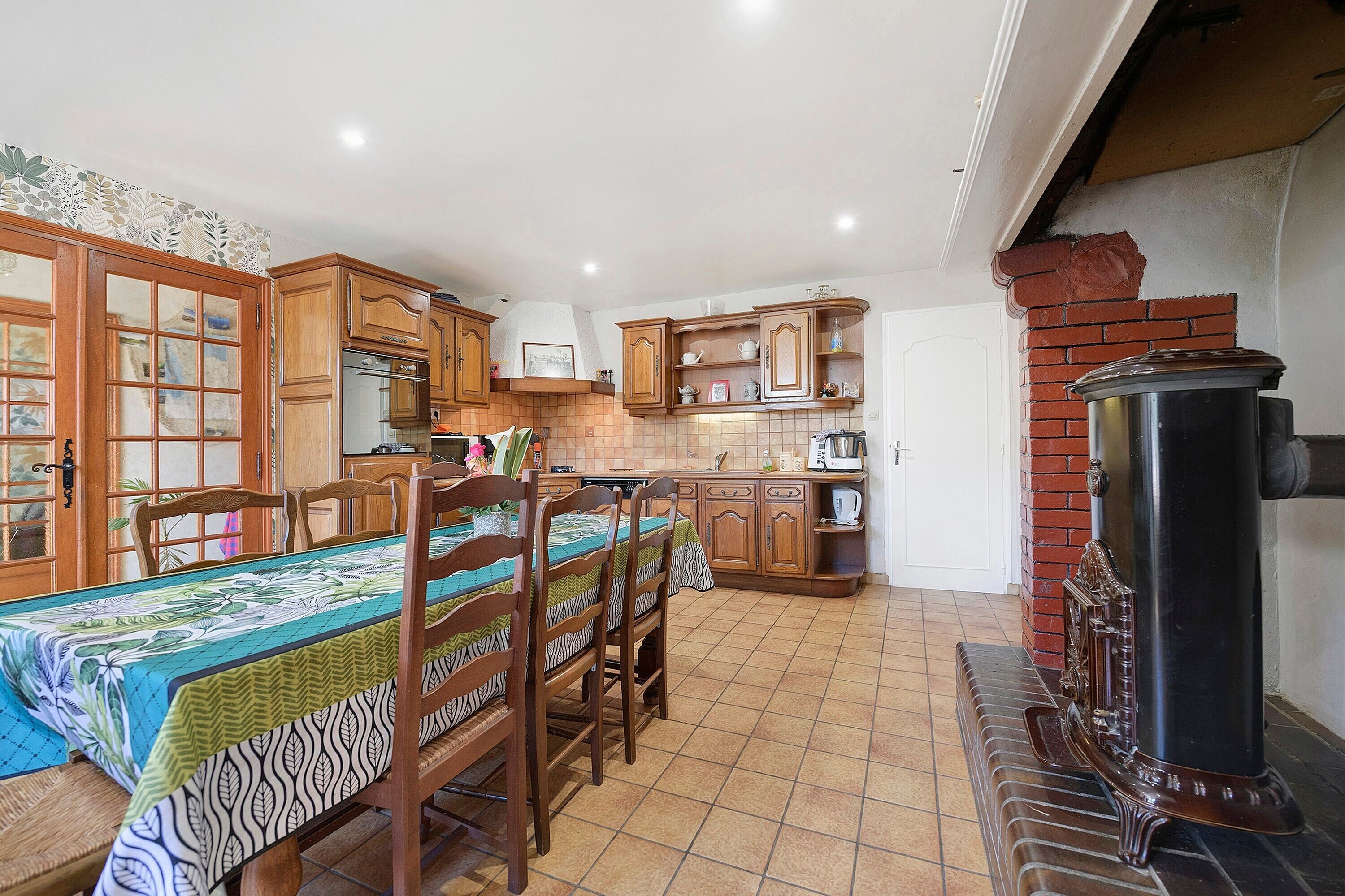 A kitchen with wooden cabinets, a dining table with chairs, and a black stove.