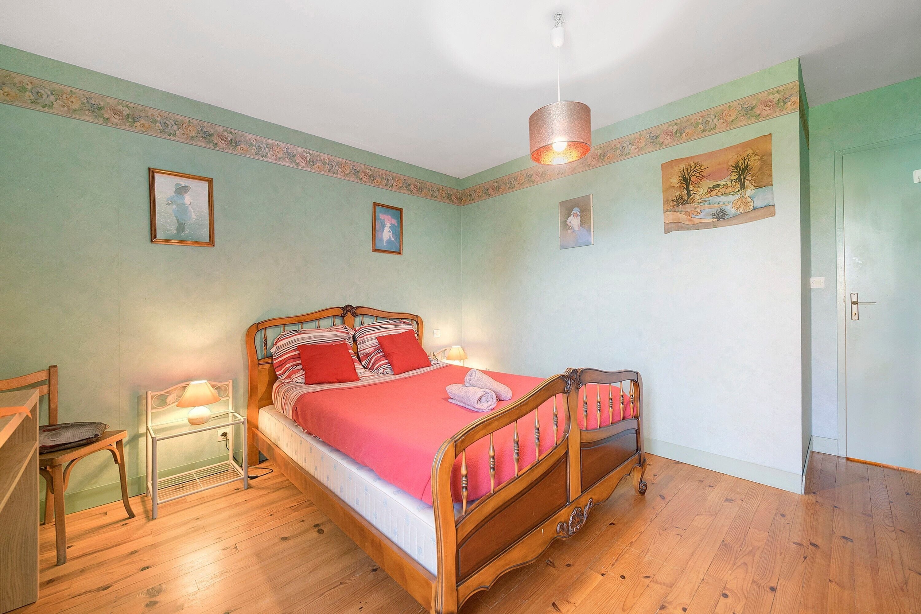 Ein Schlafzimmer mit einem hölzernen Bett, einem Nachttisch, einem Sessel und einer Lampe.