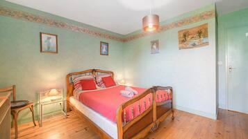 Ein Schlafzimmer mit einem hölzernen Bett, einem Nachttisch, einem Sessel und einer Lampe.