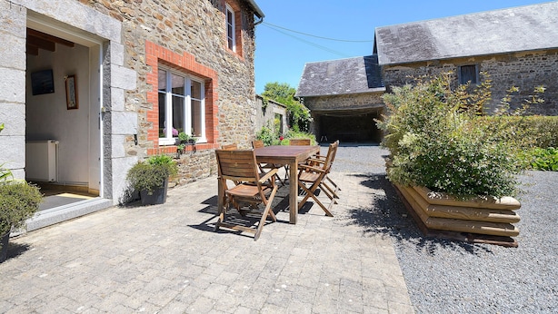 A stone building with a wooden table and chairs in the courtyard.