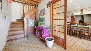 A wooden staircase leading to a room with a dining table and chairs, a potted plant, and a fireplace.