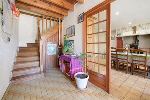 A wooden staircase leading to a room with a dining table and chairs, a potted plant, and a fireplace. - Holiday Home 'Gîte De L'arthour' with Private Garden and Wi-Fi (Notre-Dame-de-Cenilly)