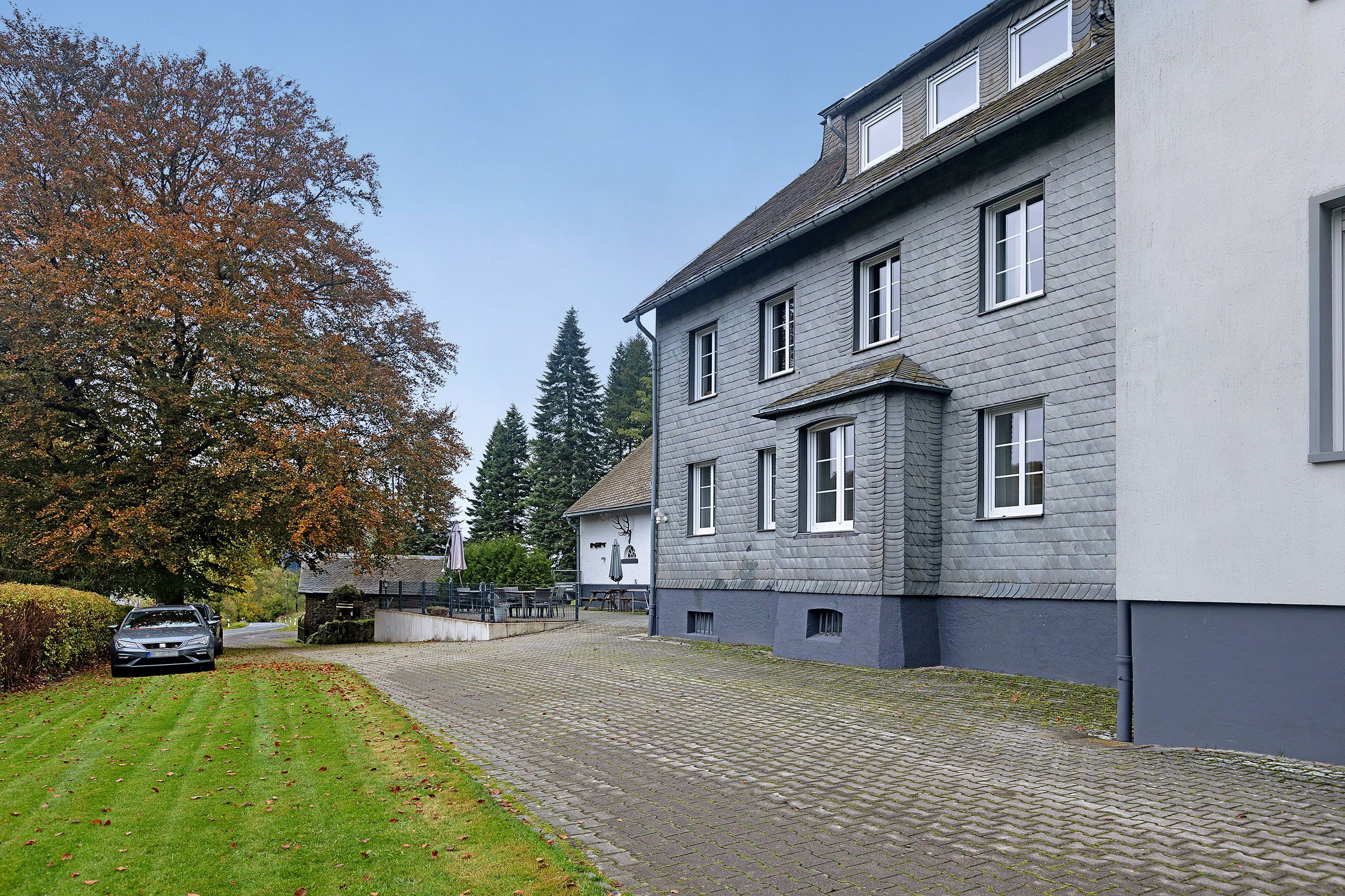 A building with a paved courtyard and a car parked in front.