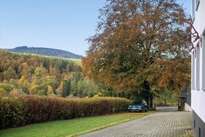 Une allée pavée mène à un bâtiment, avec un grand arbre en premier plan.