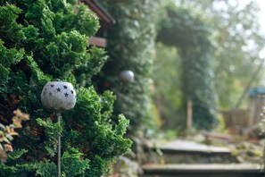 A garden with a metal sculpture on a pole, surrounded by dense green foliage.