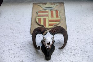 A ram skull mounted on a wall with a shield emblem in the background.