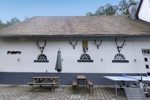 Un edificio con techo de tejas, ciervos montados como decoración y asientos al aire libre.