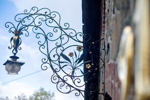 A wrought iron outdoor light fixture with a lantern, attached to a building's exterior wall.