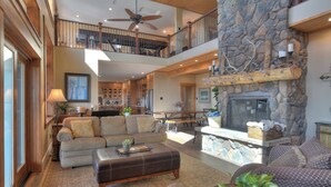 A spacious living area with a stone fireplace, a balcony, and a high ceiling fan. - Mountain Home on 8 Acres - Amazing Views / Outdoor Spaces - 19 Min to DGO (Durango)