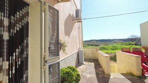 Un immeuble résidentiel doté d’une porte coulissante, d’un petit jardin et offrant une vue sur un paysage vallonné.