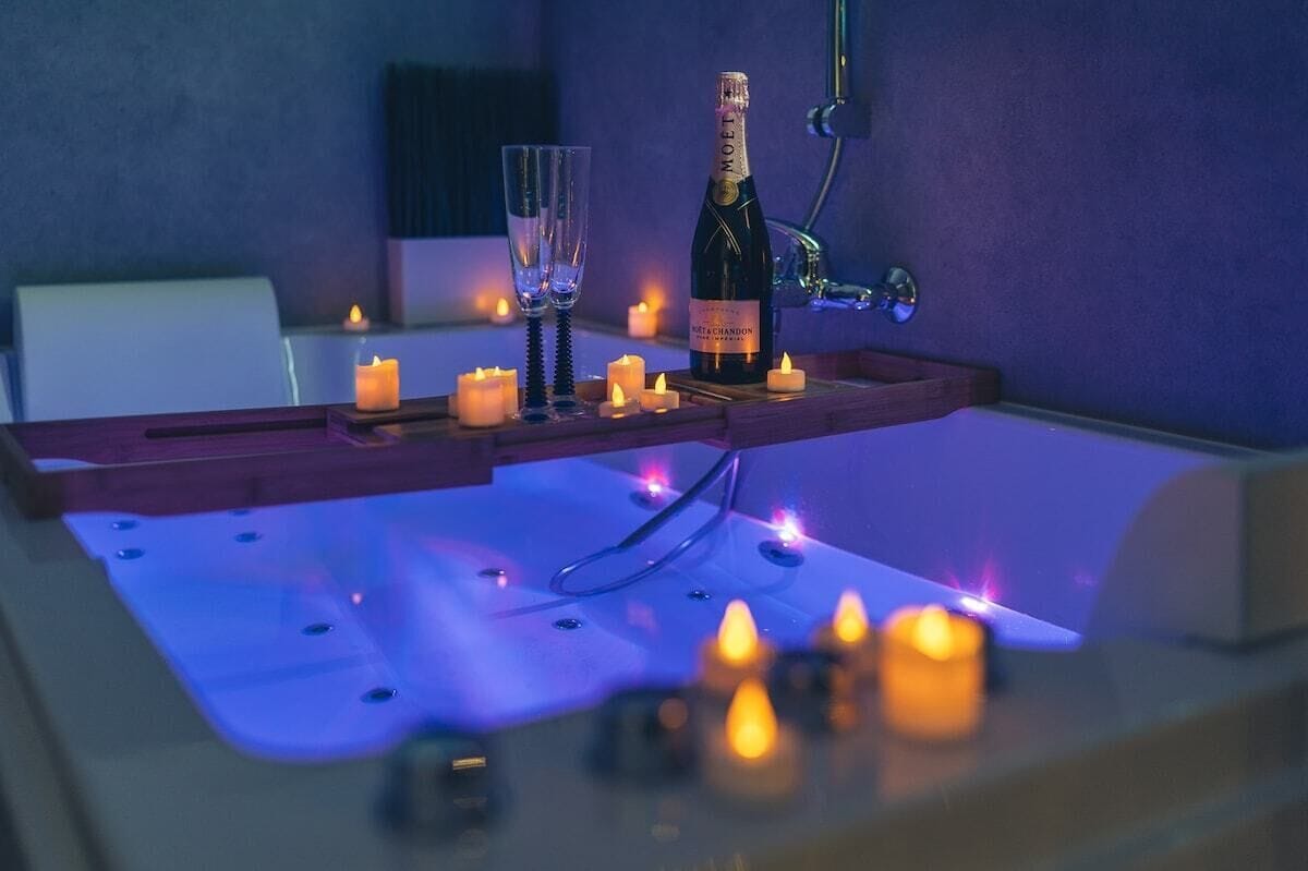 Een wellnessruimte met een jacuzzi, kaarsen en een fles champagne.