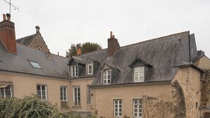 Un edificio con fachada de piedra, una pequeña ventana de arco y muros cubiertos de hiedra.