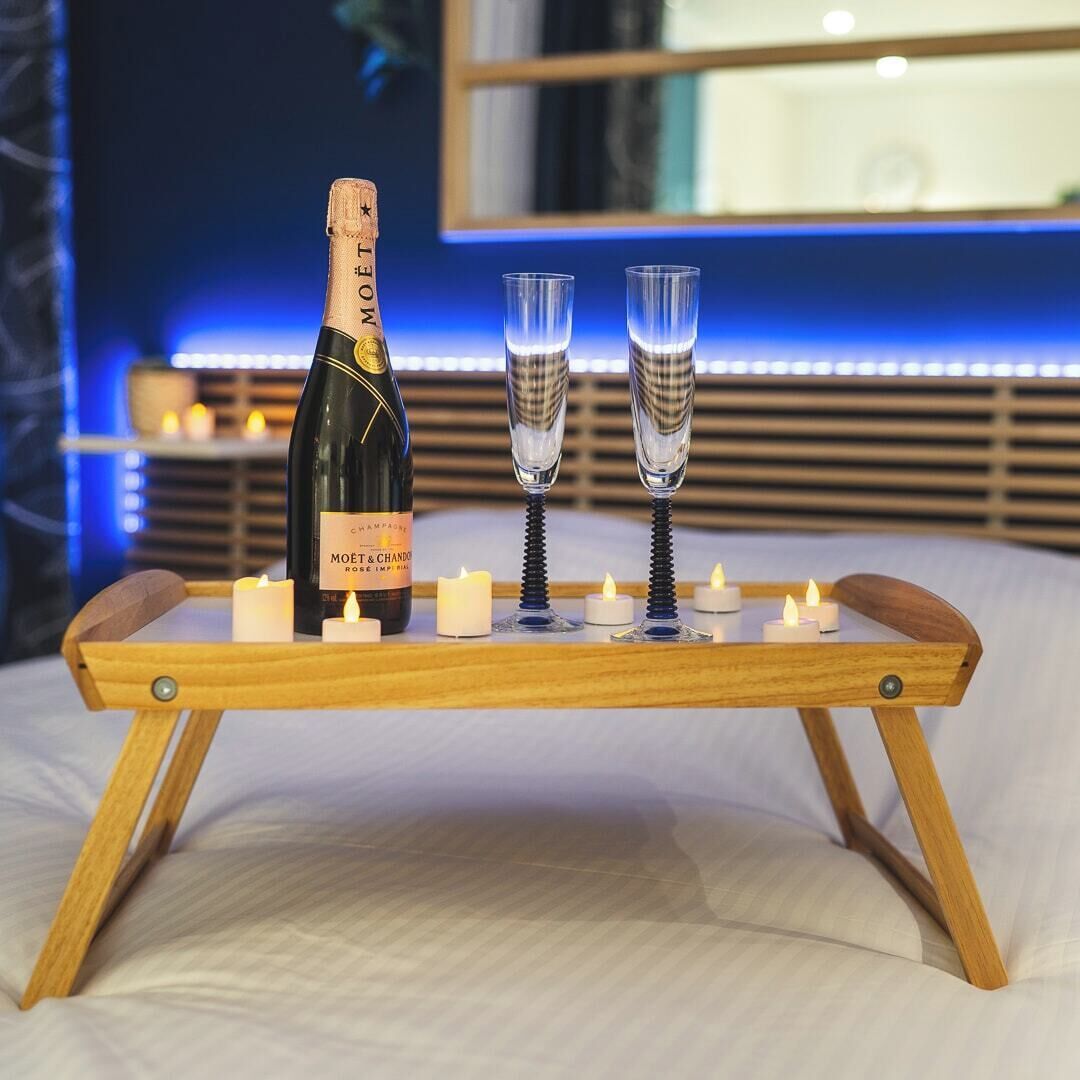 Eine Flasche Moët & Chandon Champagner, zwei Gläser und Kerzen auf einem Holzbruch.
