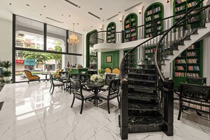 A lobby with a marble floor, a staircase, and green bookshelves. - MT Collection Legacy Hotel Ninh Binh (Hoa Lu)
