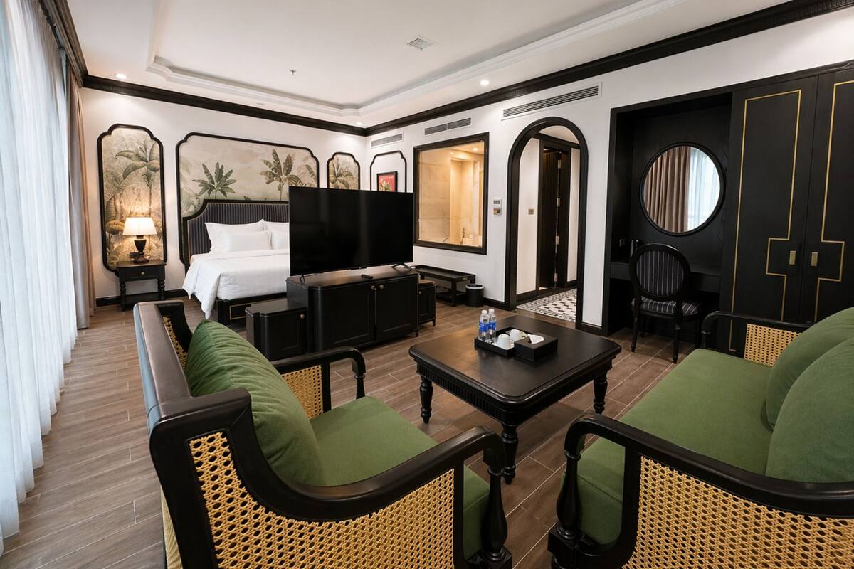 Ein Hotelzimmer mit Bett, Fernseher, Sofa, Couchtisch und Esstisch.