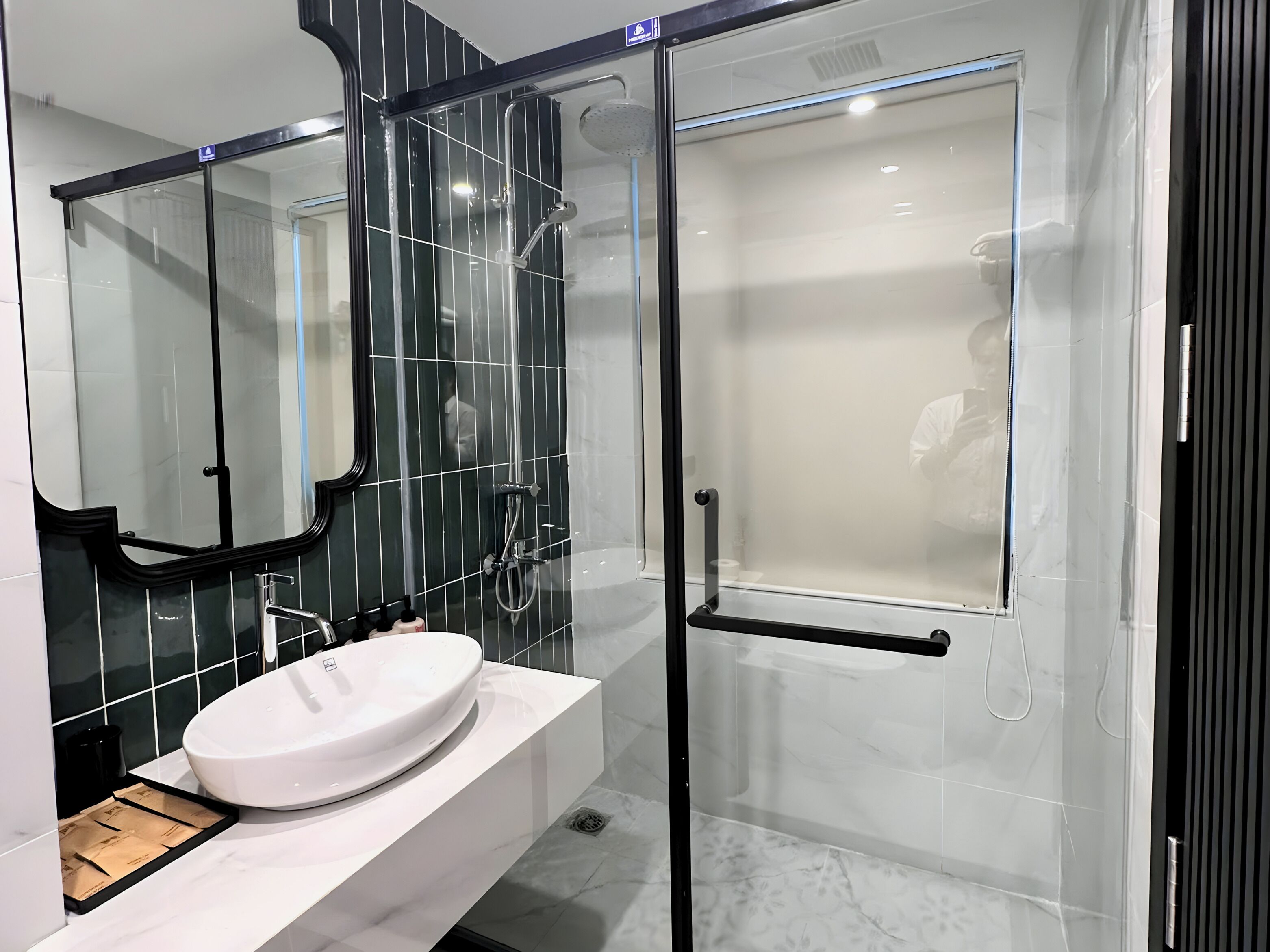 Une salle de bain moderne avec un lavabo blanc, une douche à parois de verre et un grand miroir.