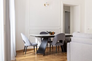 A dining area with a table, chairs, and a sofa. - This beautiful apartment is located at Largo di Pietro Brazza 26, on the fourth floor. It is very bright and features two bedrooms, one of which has an en-suite bathroom. The spacious living room, an additional bathroom, and a fully equipped kitchen with (Roma)