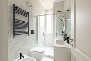 A modern bathroom with a glass shower enclosure, a white toilet, a sink, and a towel rack. - This beautiful apartment is located at Largo di Pietro Brazza 26, on the fourth floor. It is very bright and features two bedrooms, one of which has an en-suite bathroom. The spacious living room, an additional bathroom, and a fully equipped kitchen with (Roma)