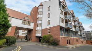 A multi-story residential building with a brick facade, multiple balconies, and a gated entrance. - Central Apartment with Parking by Guestz (Chester)