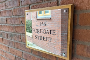 Eine Ziegelwand mit einem Schild, auf dem '156 Foregate Street' steht.