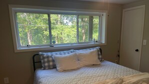 A bedroom with a bed, a window, and a door.