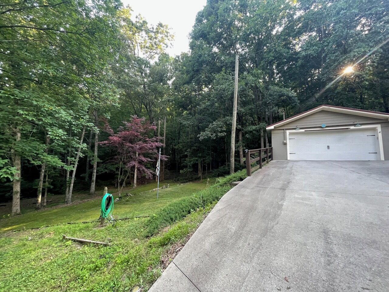 A residential property with a garage, a driveway, and a garden with trees and a lawn.