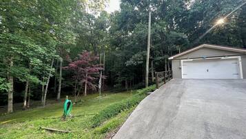 A residential property with a garage, a driveway, and a garden with trees and a lawn.
