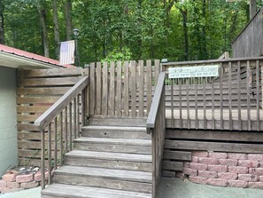 A wooden staircase with a metal handrail leading to a brick wall. A sign with coordinates is attached to the wall.