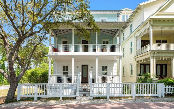 A two-story house with a porch, a white fence, and a tree. - Chasing Sunsets in Seaside: 5 bikes, crow's nest (Santa Rosa Beach)
